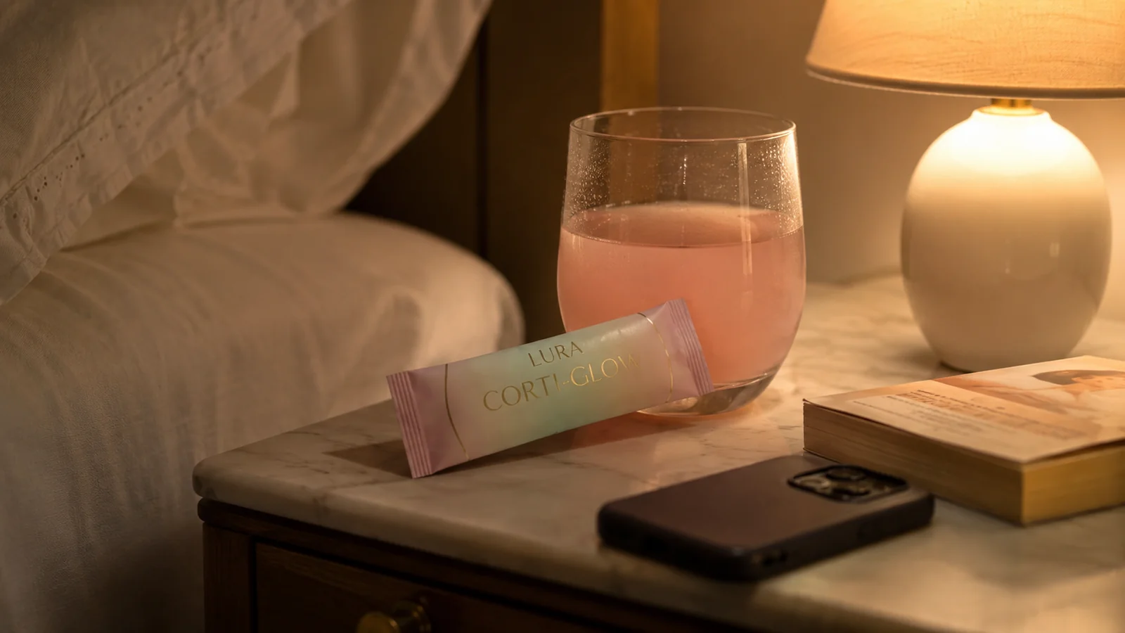 Чаша с бледорозова напитка Corti-Glow на нощно шкафче до меко осветена лампа в спокойна вечерна обстановка
