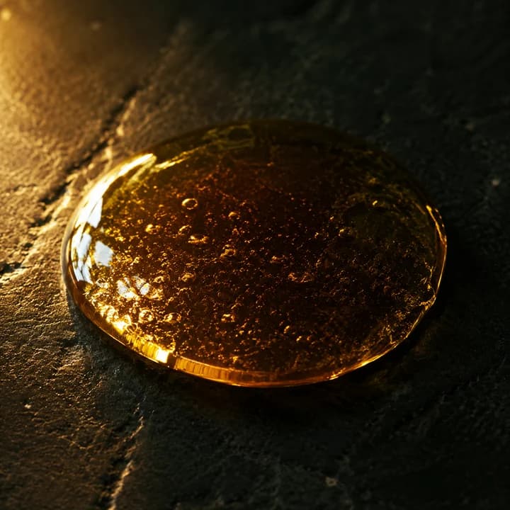A bead of thick golden oil on dark stone