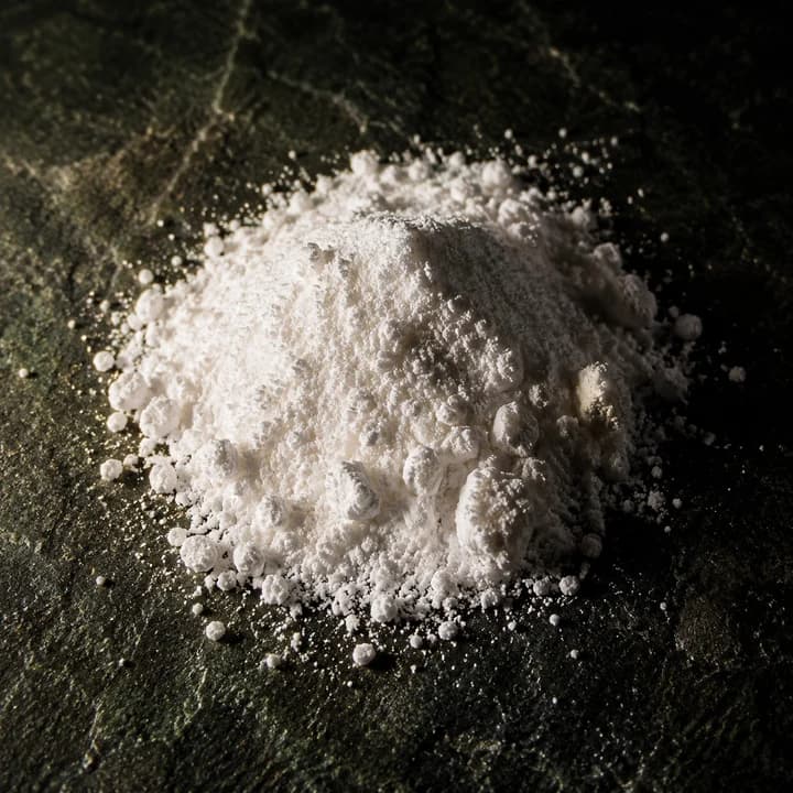 A heap of white crystalline powder on dark stone